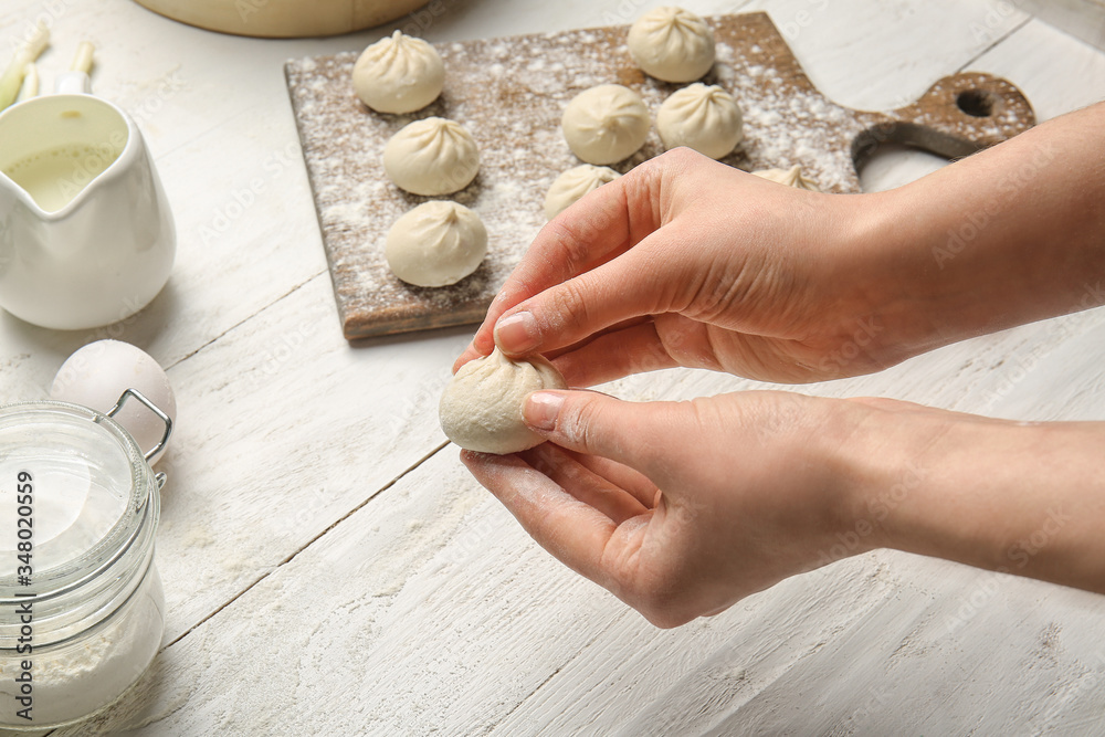 Woman preparing tasty dumplings on table