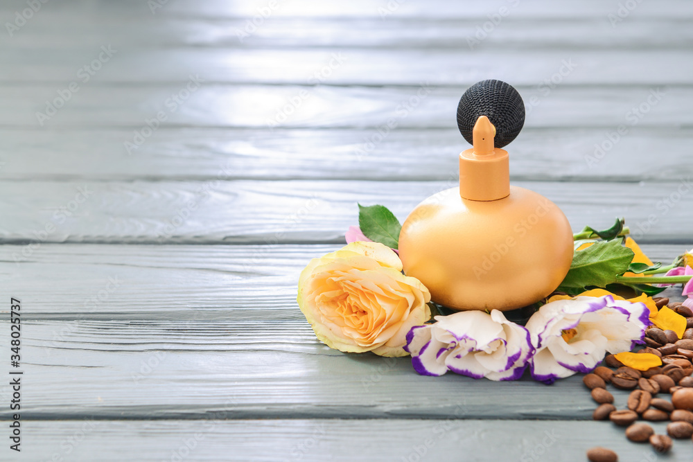 Bottle of perfume with flowers on wooden background