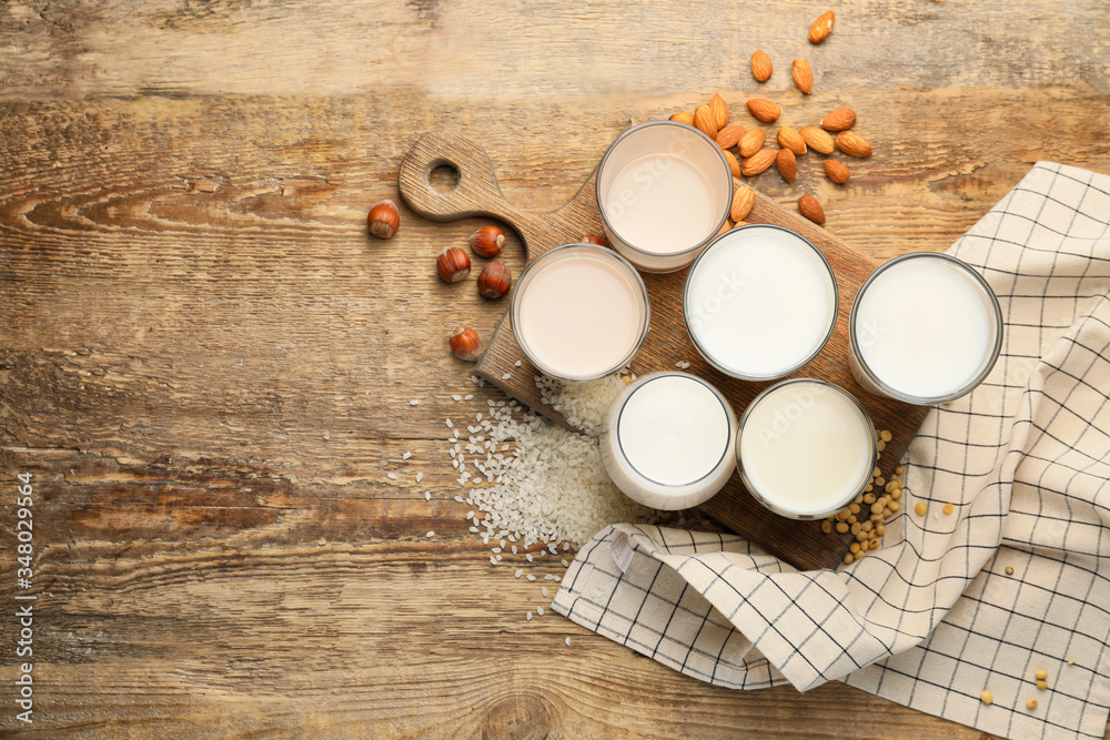 Glasses of different milk on wooden background