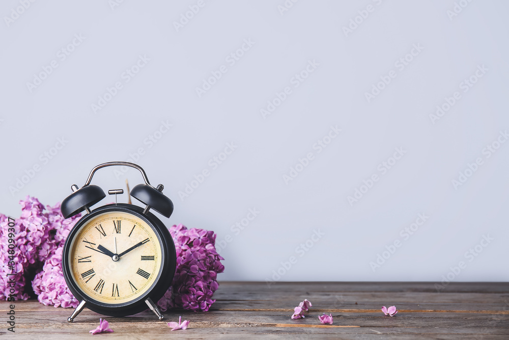 Alarm clock and flowers on table. Spring time