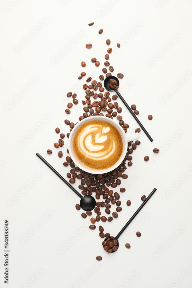 Cup of tasty cappuccino with roasted coffee beans on white background