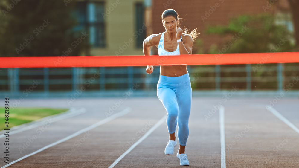 Beautiful Fit Female Runner Crossing the Finish Line on a Professional Sports Arena. Athletic Woman 