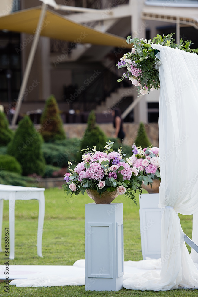 a large vase of flowers stands on a white pedestal in the park, a wedding decoration, a festive deco