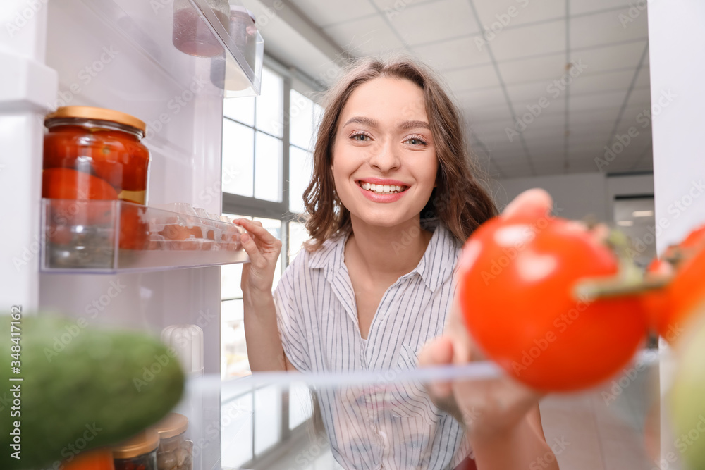 Woman with fresh products in fridge, view from inside