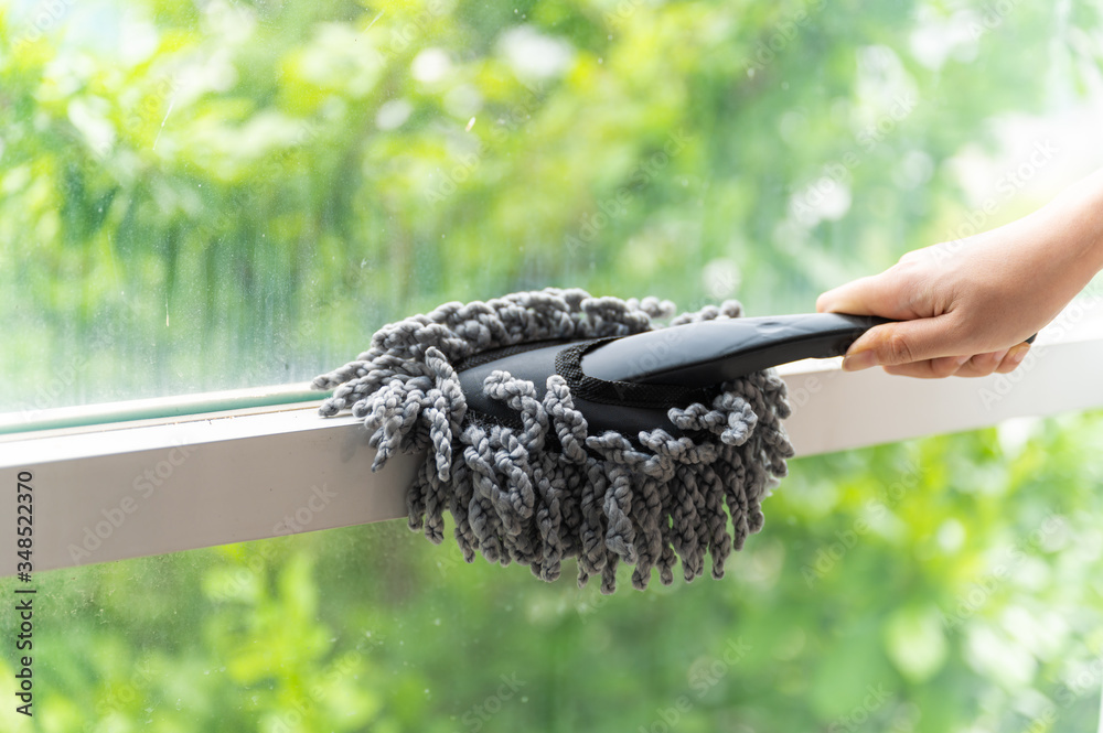 Close up young Asian woman holding dust wiper cleaning house window