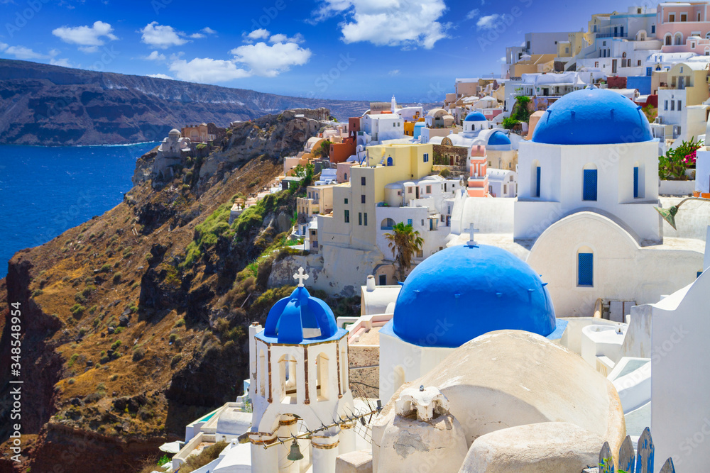 Blue church domes and white houses in the beautiful Oia town on the Santorini island, Greece.