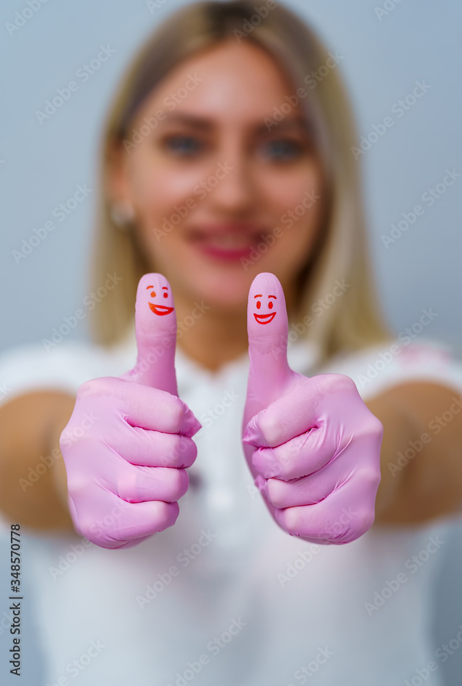 Dentist woman with pink gloves. Showing cool sign. Red smiles on thumbs.