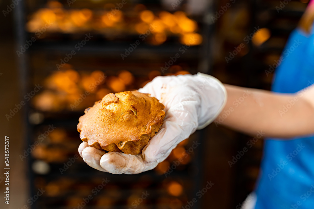 Hand holding cake or muffin. Factory oven background.