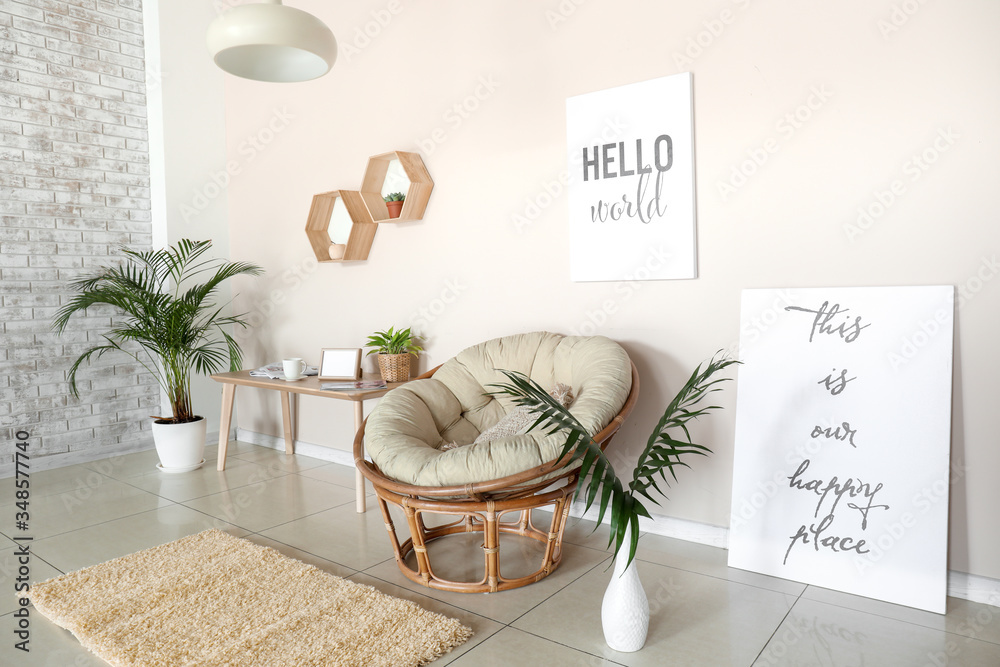 Comfortable armchair, table and houseplants in interior of living room