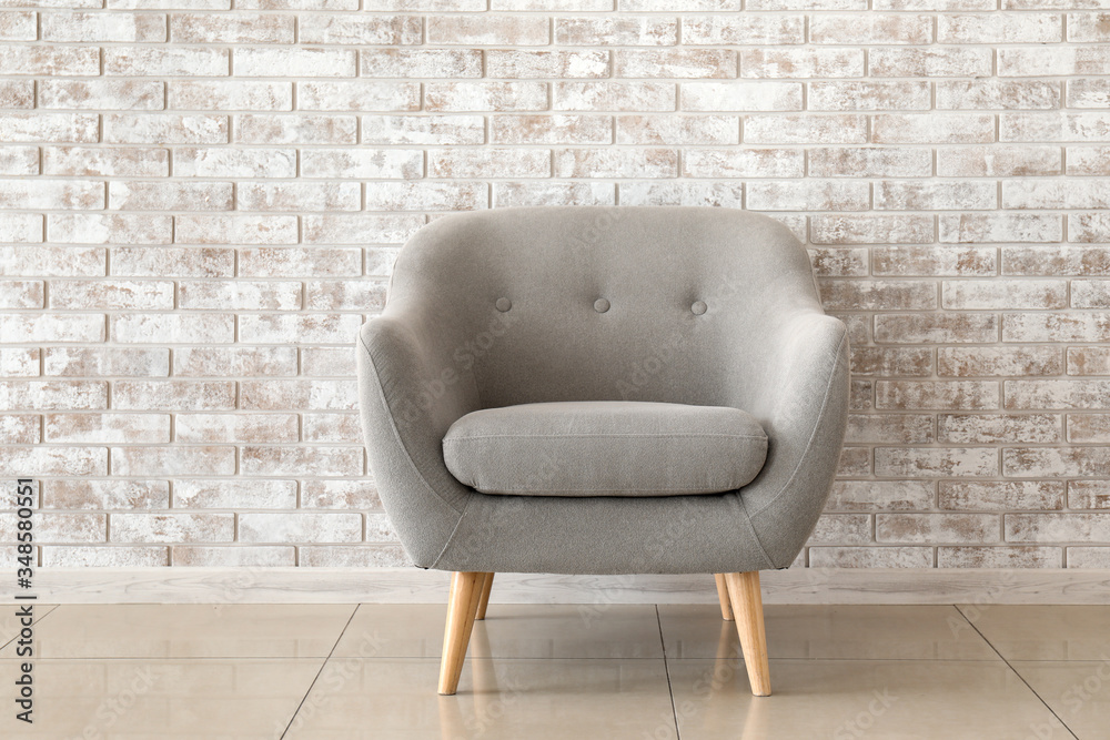 Comfortable armchair near brick wall