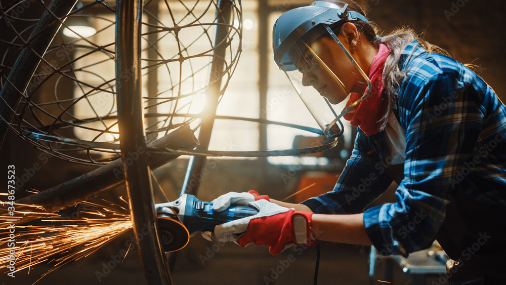 Close Up of Young Female Fabricator in Safety Mask. She is Grinding a Metal Tube Sculpture with an A