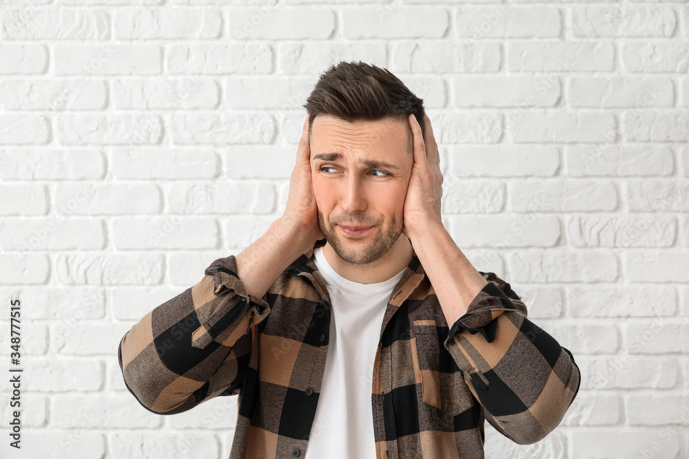 Young man suffering from loud noise on white background