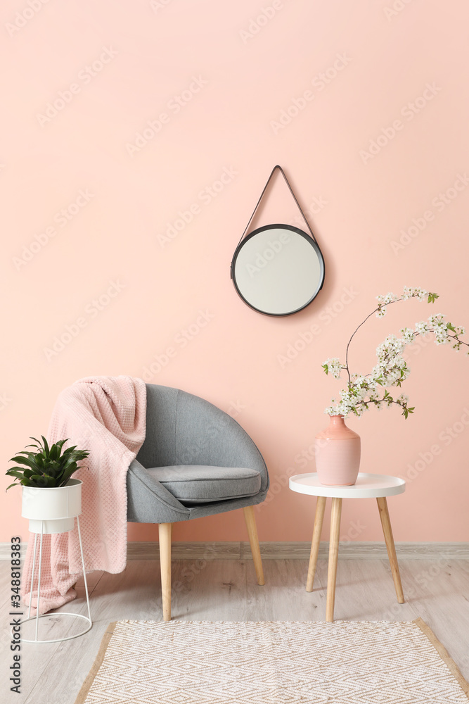 Interior of living room with stylish mirror and blooming tree branches