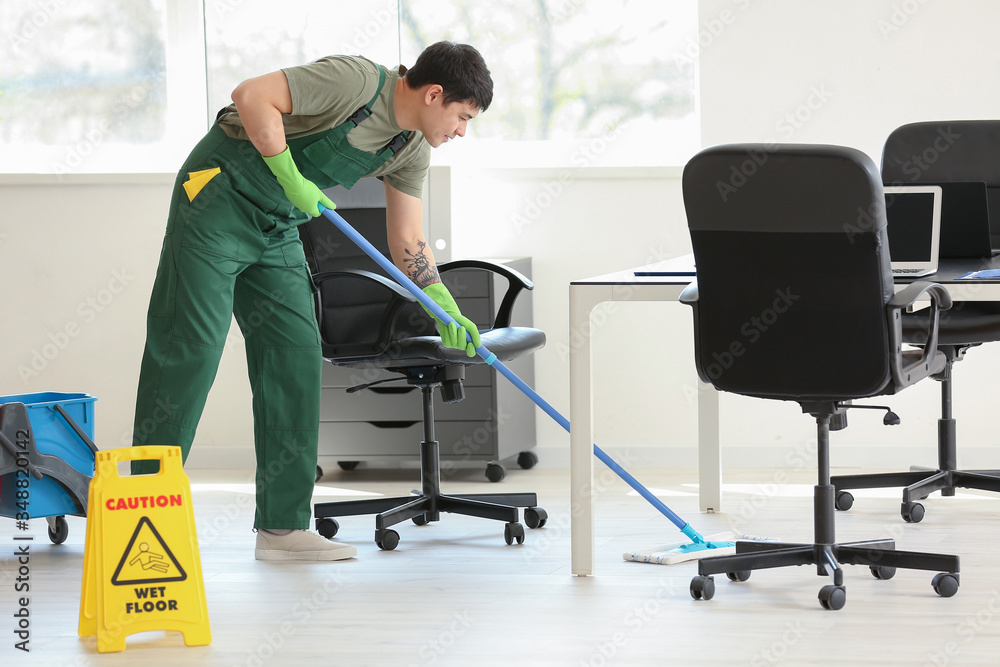 Male janitor mopping floor in office