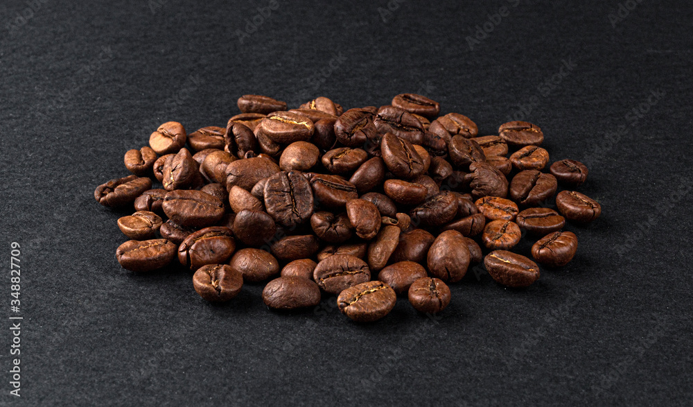 Heap of roasted coffee beans on black background