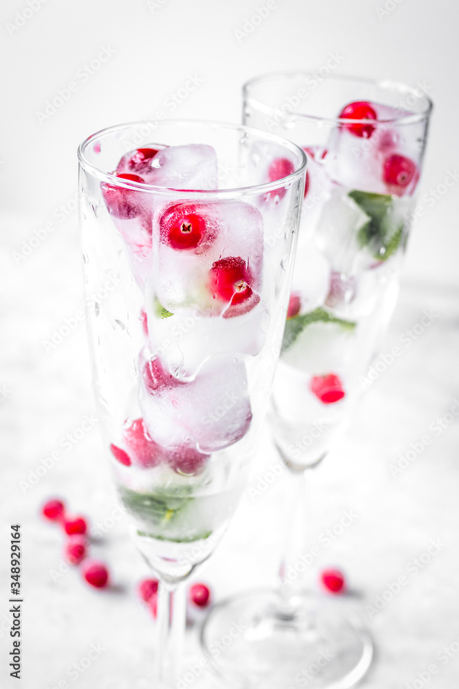 mint and red berries in ice cubes in glasses white background