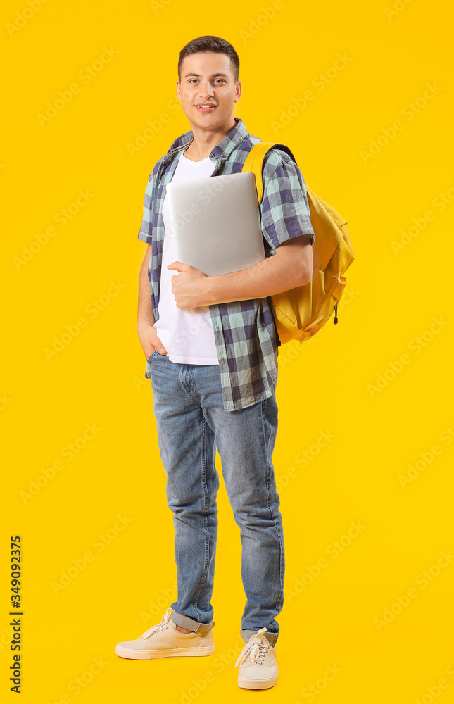 Male student with laptop on color background