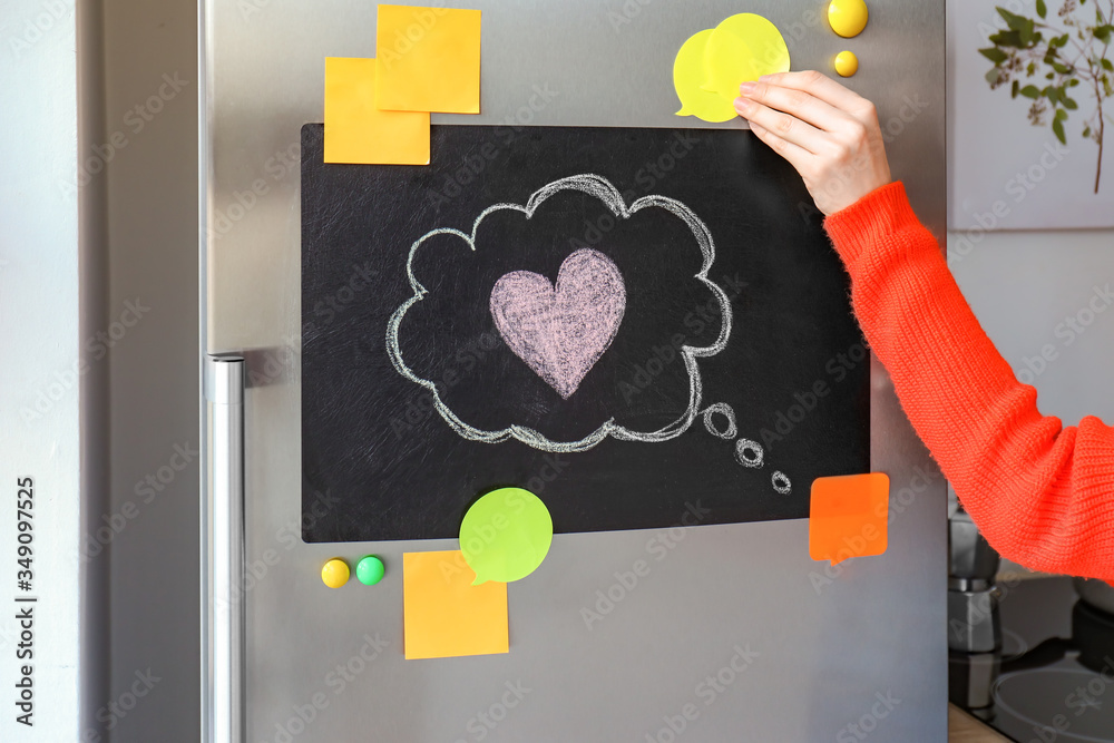 Young woman near refrigerator in kitchen