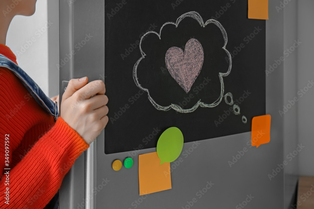 Young woman opening refrigerator in kitchen