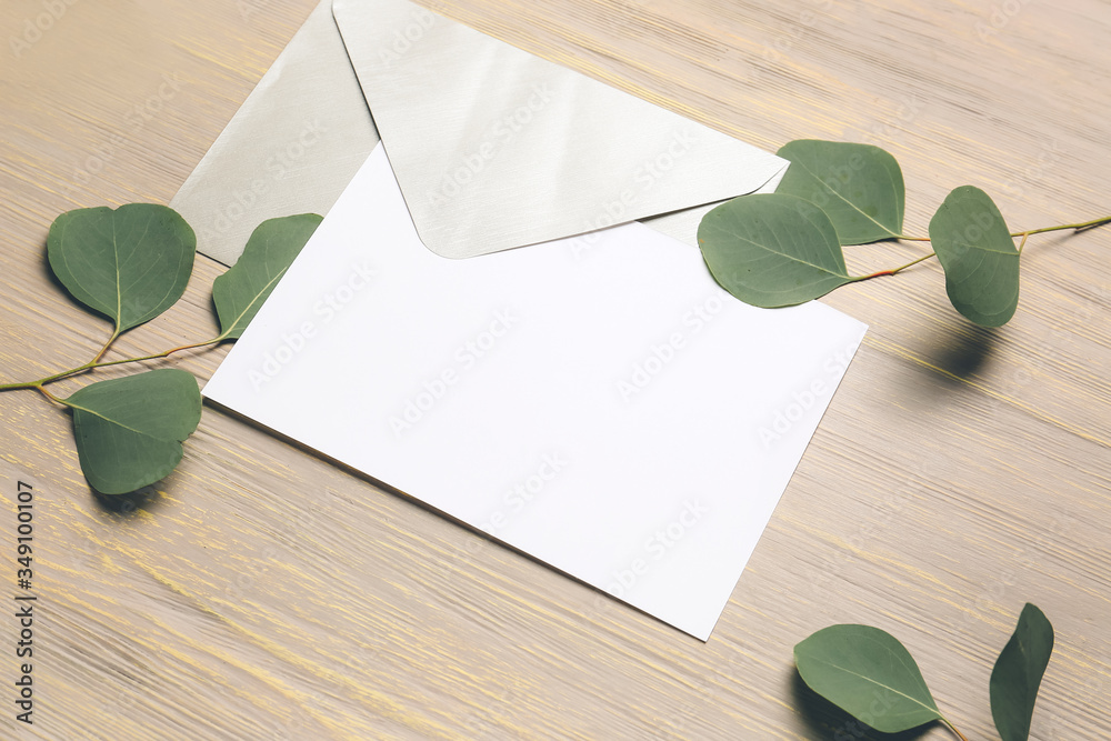 Composition with blank card, envelope and leaves on wooden background