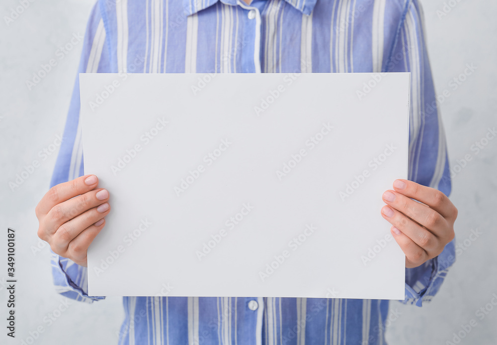 Woman with blank card on light background