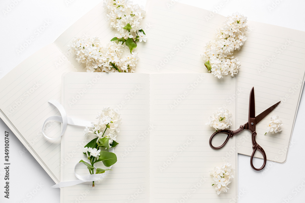 Notebooks, beautiful lilac flowers and scissors on white background