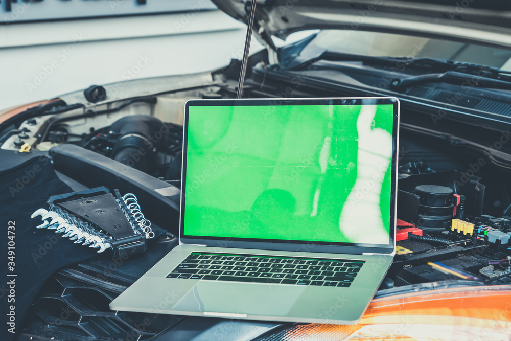 Laptop computer on car hood for engine diagnostic. Car garage repair service concept.