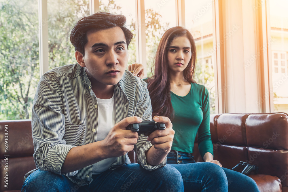 Young Asian couple suffers from computer games addiction. Family problem concept.