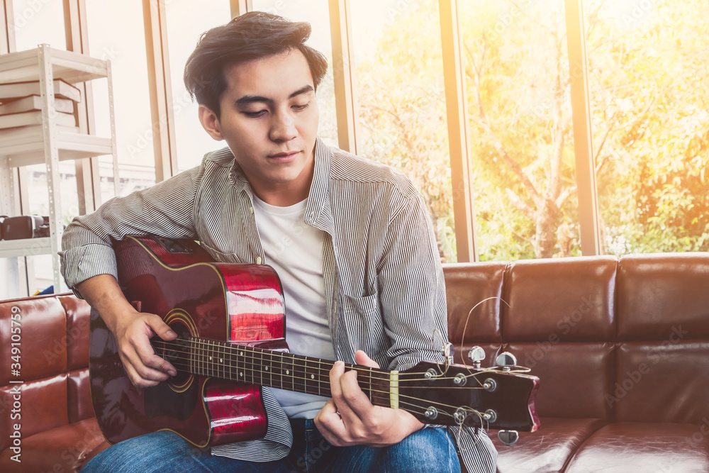 Young guitar player holding his guitar at home. Music and song concept.