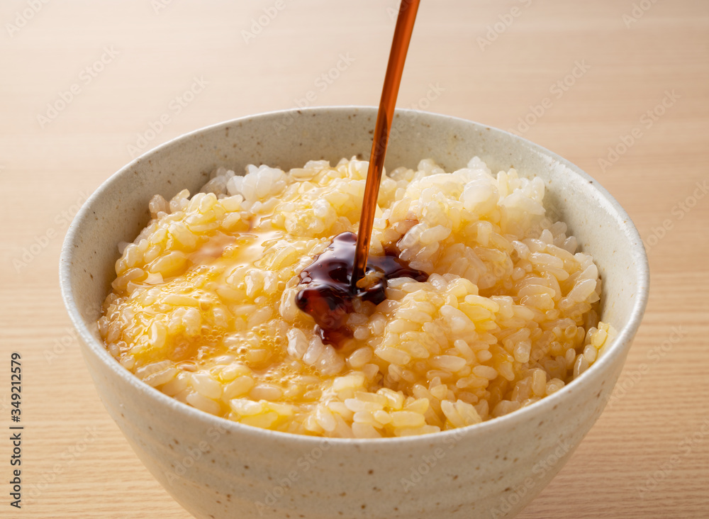 pouring soy sauce over rice with an egg