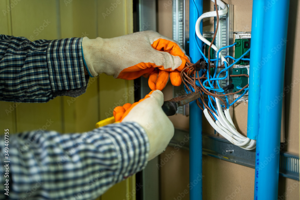 Young repairman fixing electrical,Electrician checking wires in electrical box with pliers in corrid