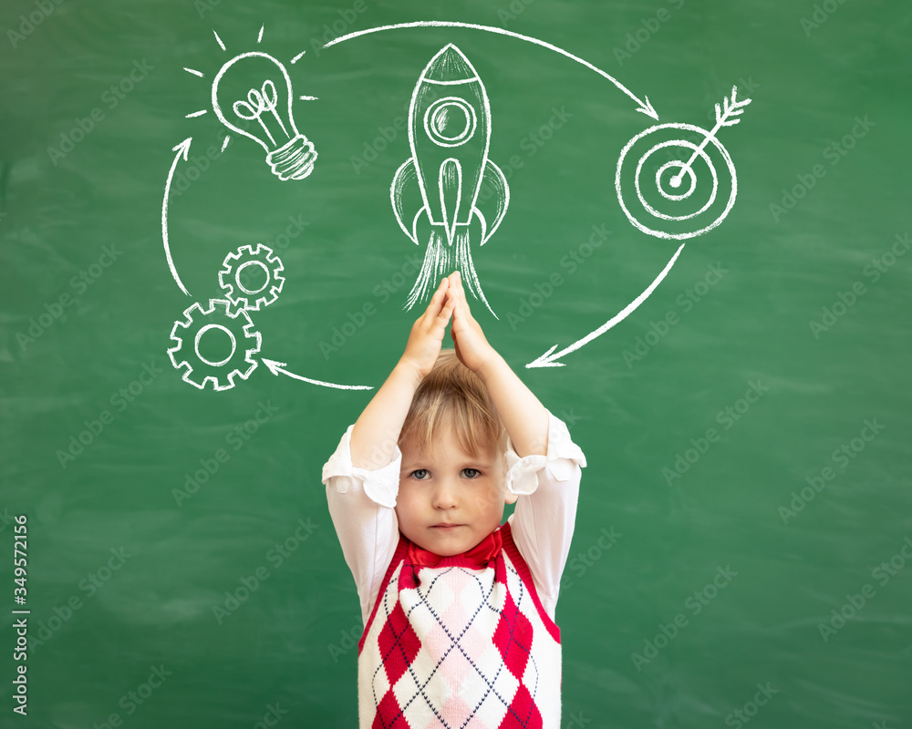 Happy child student against green chalkboard