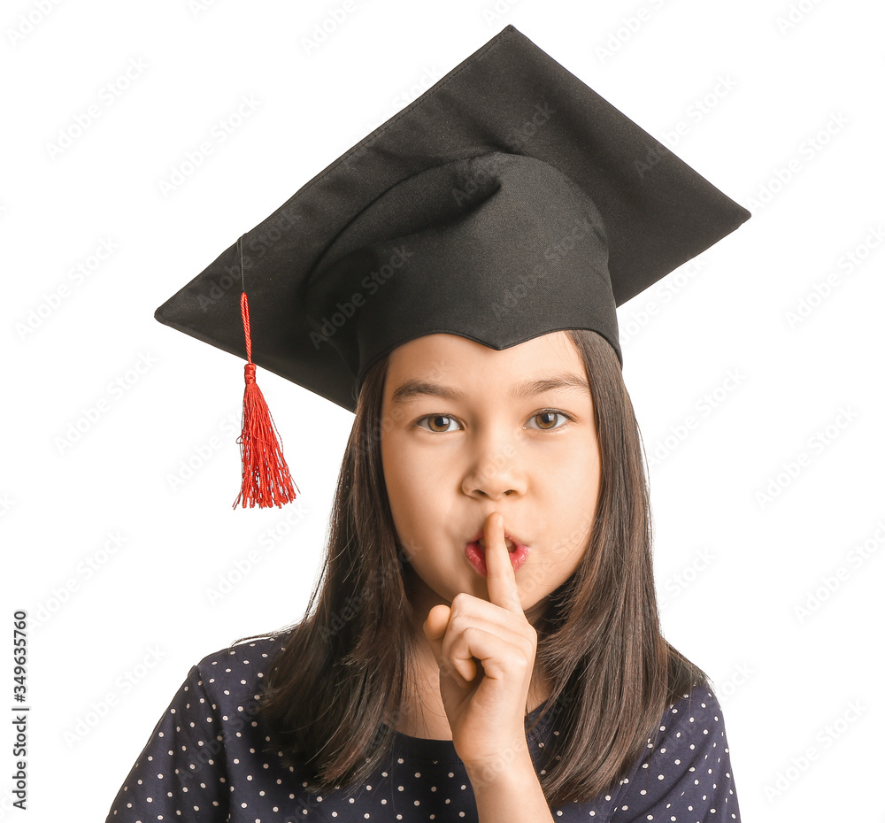 Little girl in graduation hat showing silence gesture on white background