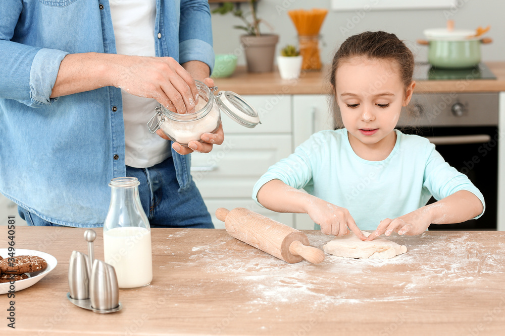 Happy father with little daughter making dough together in kitchen