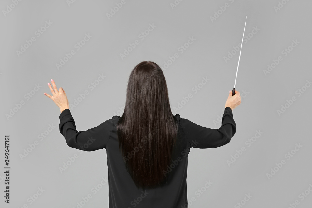 Young female conductor on grey background