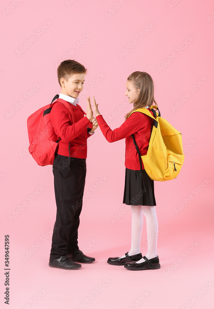 Cute little pupils giving each other high-five on color background