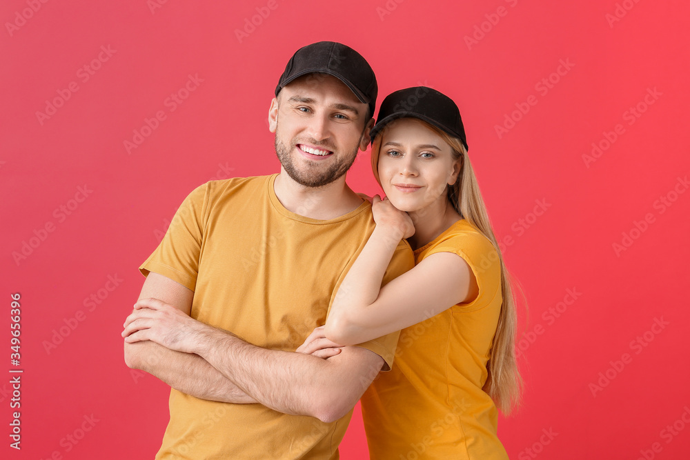 Young couple in stylish caps on color background