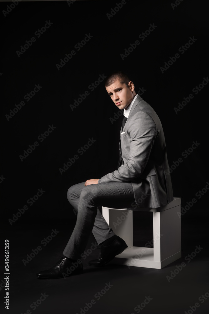 Handsome young man in elegant suit on dark background