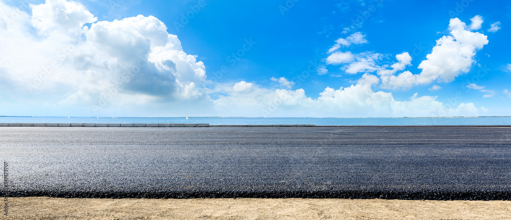 阳光明媚的日子里，沥青路面和湖面上有天空的云朵景观。