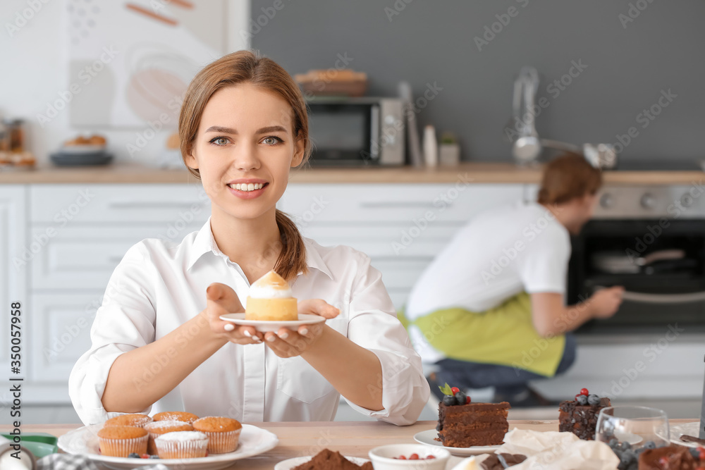 Female confectioner with tasty desserts in kitchen