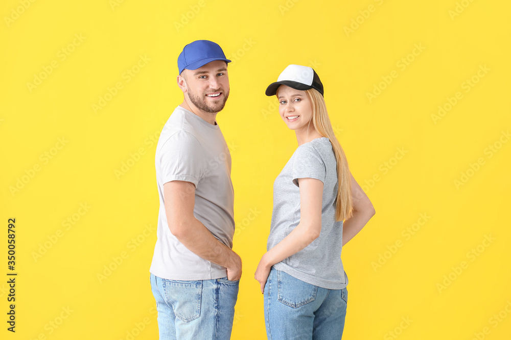 Young couple in stylish caps on color background