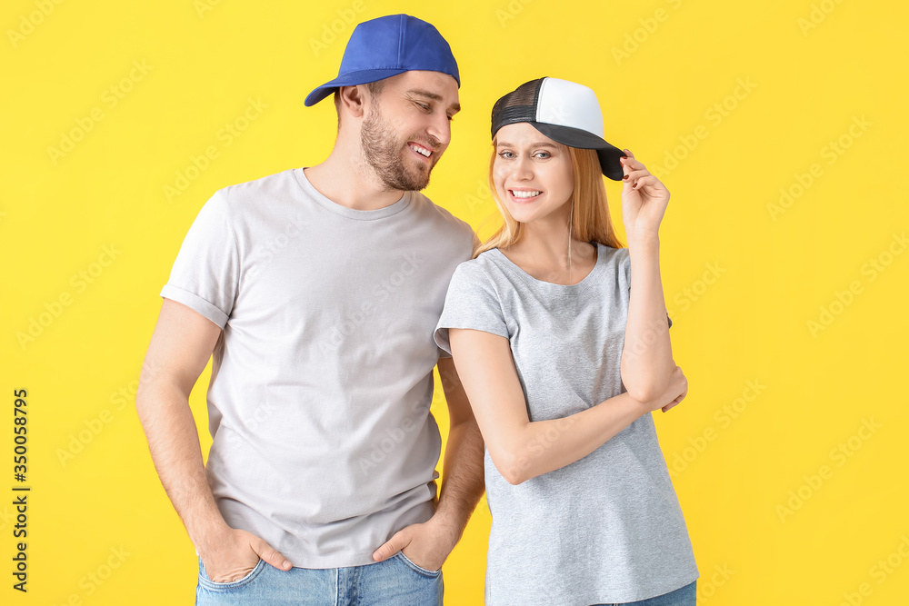 Young couple in stylish caps on color background