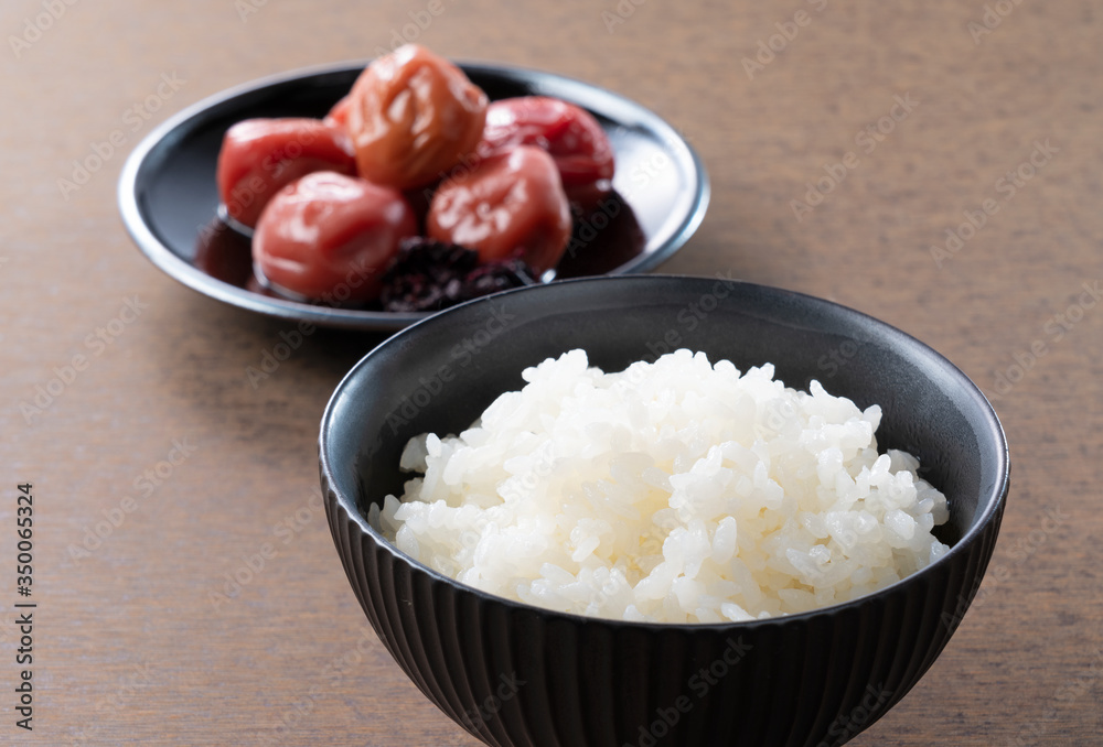 木制背景下的日本腌李子和新鲜煮熟的米饭