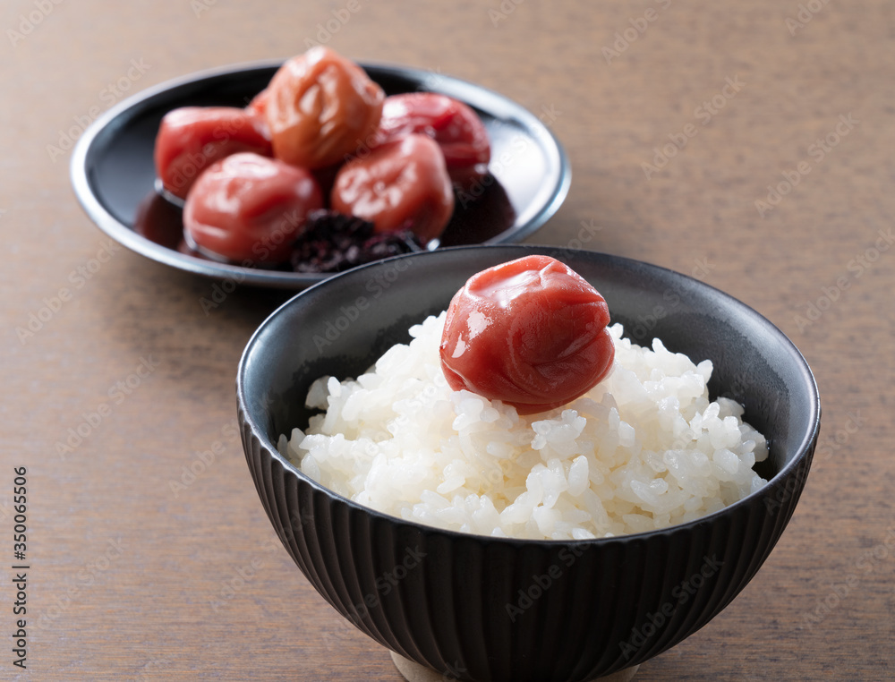 Japanese pickled plums and freshly cooked rice set against a wooden backdrop