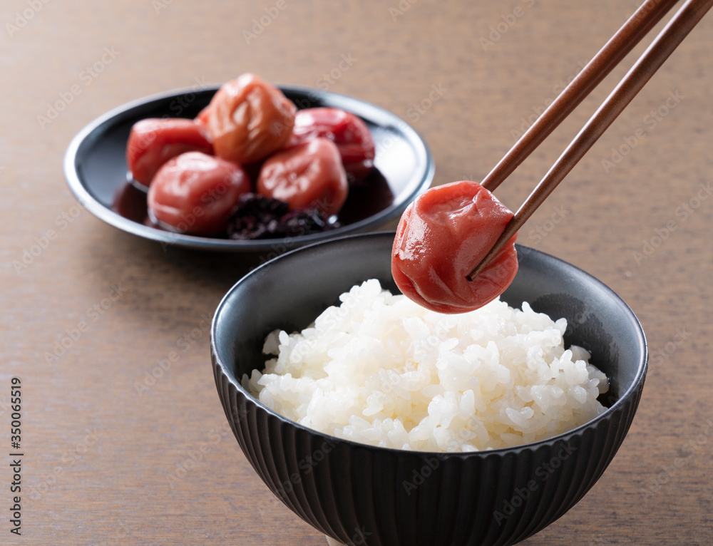 木制背景下的日本腌李子和新鲜煮熟的米饭