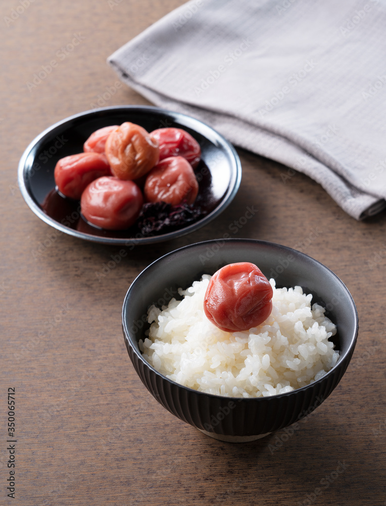 木制背景下的日本腌李子和新鲜煮熟的米饭