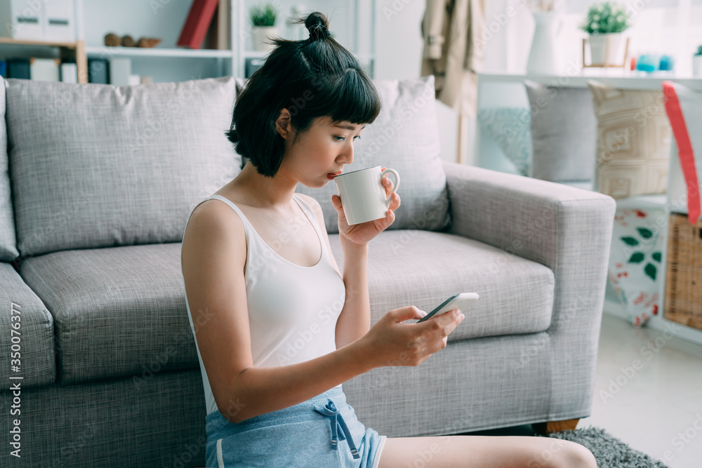 Texting to boyfriend. beautiful young asian chinese woman in shorts holding cup of coffee and using 