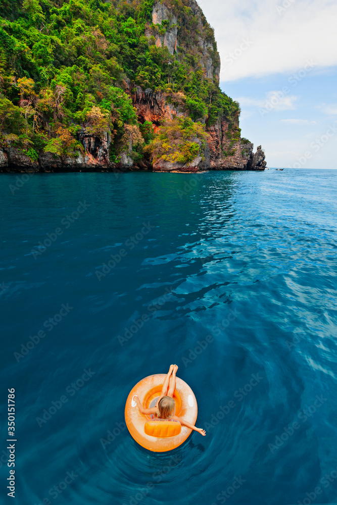 Photo of happy child swimming with fun on inflatable floating ring in sea water pool. Family travel 