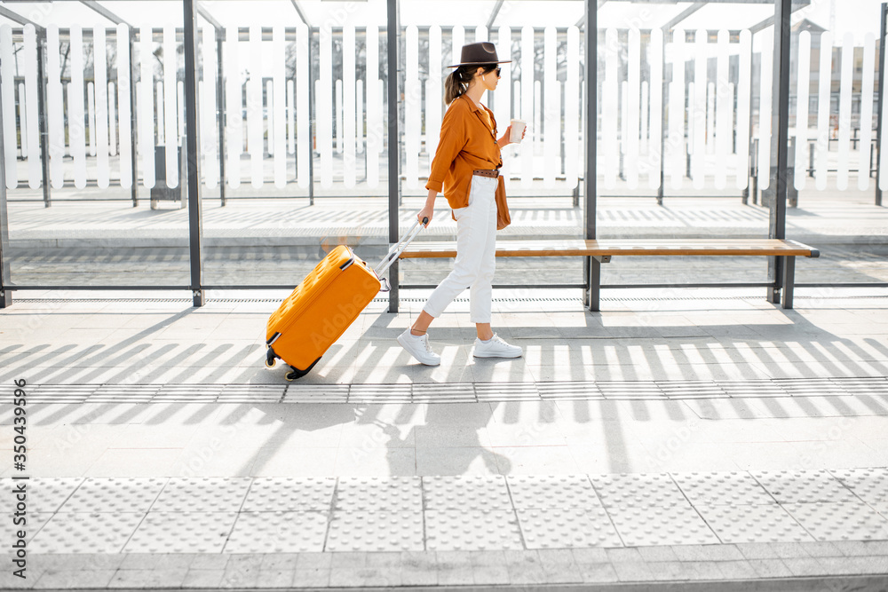 在运输站提着行李箱的年轻女性旅行者