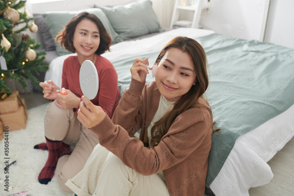 Two women together on a care treatment with face rollers for skin lifting.